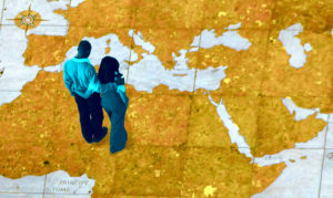 Un homme et femme sur un planisphère géant regardent le Moyen-Orient