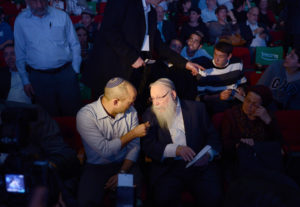 Naftali Bennett (à gauche), député de la coalition Yamina du parlement israélien, s'entretient avec le rabbin Haim Druckman. Ils sont au milieu d'une foule de croyants. 
