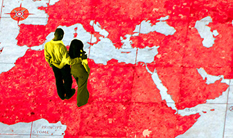 Un couple se tient débout sur le planisphère géant de Lisbonne et regarde le Moyen-orient