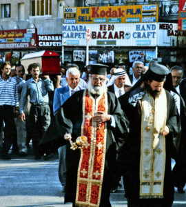 deux popes orthodoxes guident un enterrement et marchent devant un cercueil porté sur l'épaule par des hommes