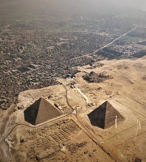 panorama aérien du Caire avec les pyramides qui émergent au milieu du désert à côté de la ville