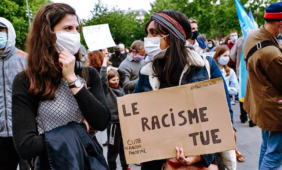 Duex filles avec une panacrte qui dit "Le racisme tue" lors d'une manifestation antiraciste