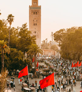 Manifestation à Marrakech avec des drapeau marocains en premier plan et la mosquée en arrière plan