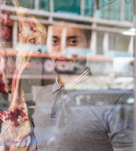 Un jeune boucher libanais derrrière les reflêts d'une vitrine