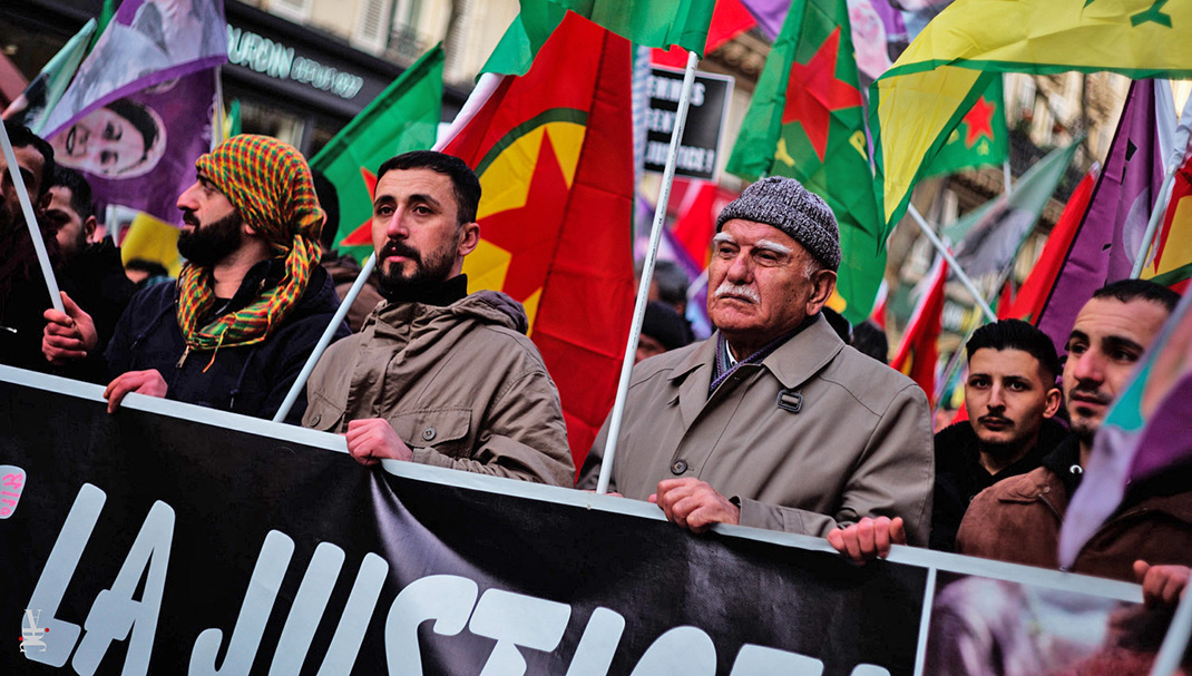 Un jeune et un ancien brandissent une banderole lors de la manifestation avec la gauche kurde