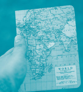 Une main tient un cahier avec la carte du monde sur la couverture