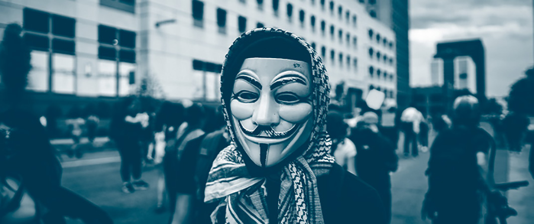 Un manifestant avec le masque du personnage de "V pour Vendetta" et un keffieh autour de sa tête