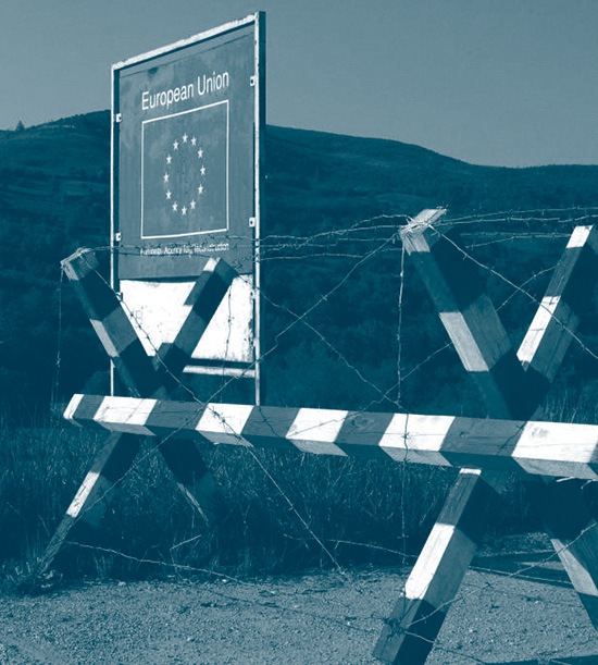barrière rouge et blanc entourée de barbelée à la frontière de la Serbie avec un drapeau de l'Union européenne