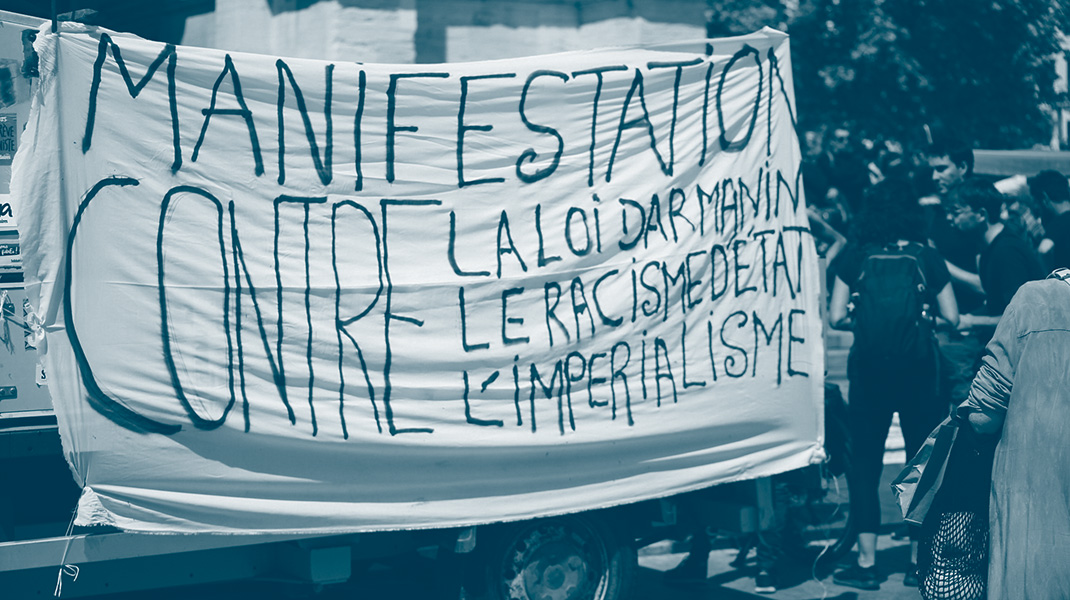 Une pancarte avec le texte "manifestation contre la loi Darmanin, le racisme et l'impérialisme"