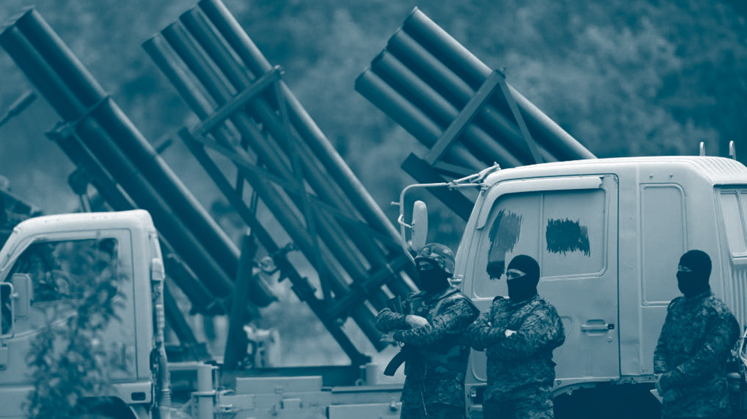Combattants du Hezbollah avec une cagoule devant une batterie de lanceurs de roquettes durant un exercice militaire