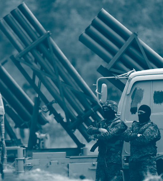 Combattants du Hezbollah avec une cagoule devant une batterie de lanceurs de roquettes durant un exercice militaire