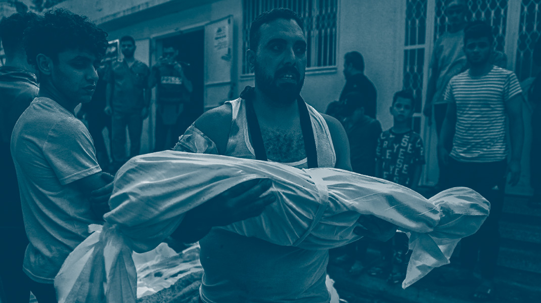 Un homme tient le corps d'un enfant mort enveloppé dans un drap au milieu de ruines à Gaza