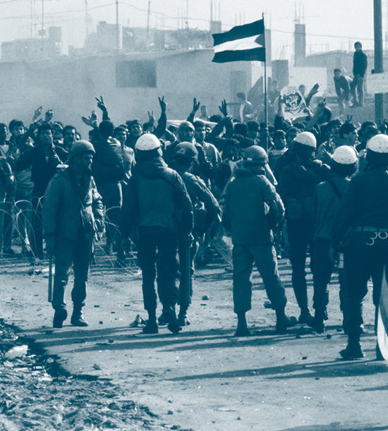 Un groupe de manifestants brandissant un drapeau palestinien à Gaza pendant la 1er intifada devant les troupes antiémeute israélienne