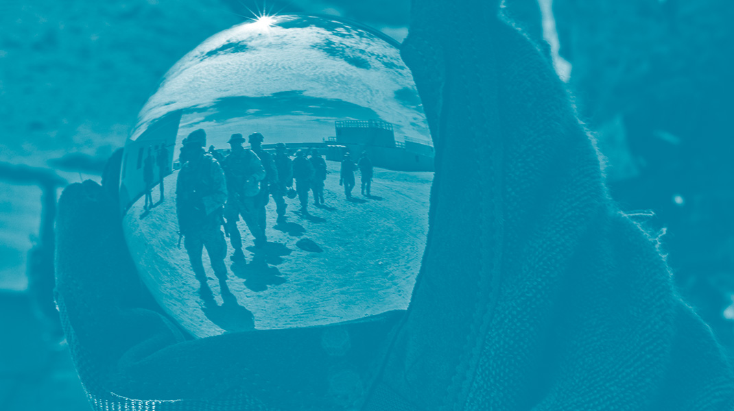 Un soldat de l'armée des États-Unis tiens dans sa main une bulle en verre avec le reflet d'autres marines dans le désert