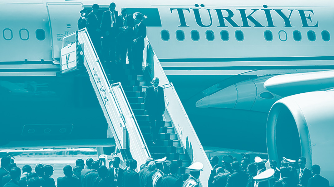 Erdogan, au milieu d'un escalier, descend de l'avion présidentiel lors d'une visite officielle en Iran. Devant lui une foule l'attend en bas de l'escalier