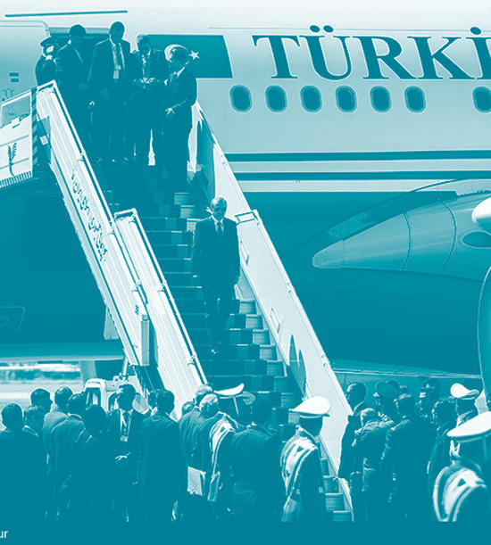 Erdogan, au milieu d'un escalier, descend de l'avion présidentiel lors d'une visite officielle en Iran. Devant lui une foule l'attend en bas de l'escalier