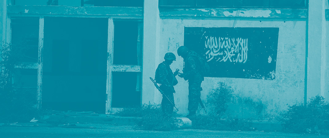 Deux soldats parlent entre eux devant le drapeau du groupe islamiste Al Shabaab, affilié d'Al-Qaeda, dessiné sur un mur