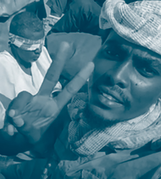 Un milicien soudanais fait le signe de la victoire avec des prisonniers bandés derrière lui