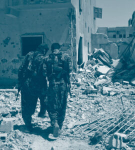 Deux combattants, membres des Forces démocratiques syriennes entre les décombres à Raqqa, parlent entre eux en tournant le dos au photographe