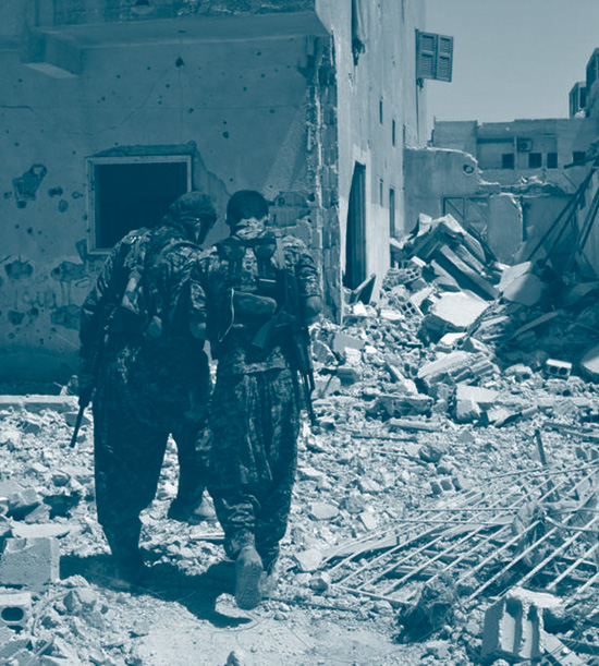 Deux combattants, membres des Forces démocratiques syriennes entre les décombres à Raqqa, parlent entre eux en tournant le dos au photographe