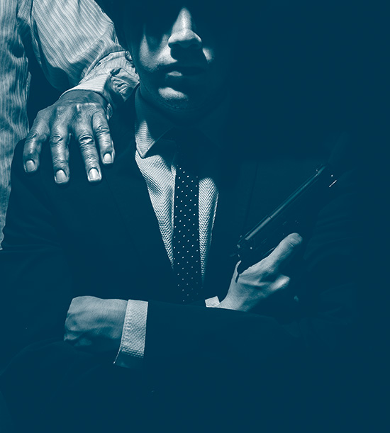 Un mafieux avec un pistolet dans sa main. derrière lui un homme tient une main sur son épaule