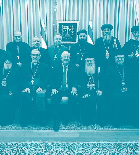 Le président israélien Reuven Rivlin et les chefs de la communauté chrétienne en Israël posent pour une photo colelctive. derrière eux deux drapeaux israéliens