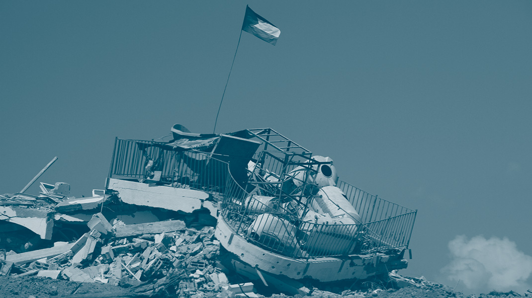 bâtiment à Gaza complètement détruit sur lequel est hissé un drapeau palestinien