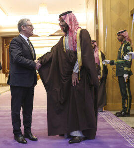 Mohamed ben Salmane et le premier ministre anglais Keir Starmer se serrent la main dans le couloir entourés de gardes saoudiennes