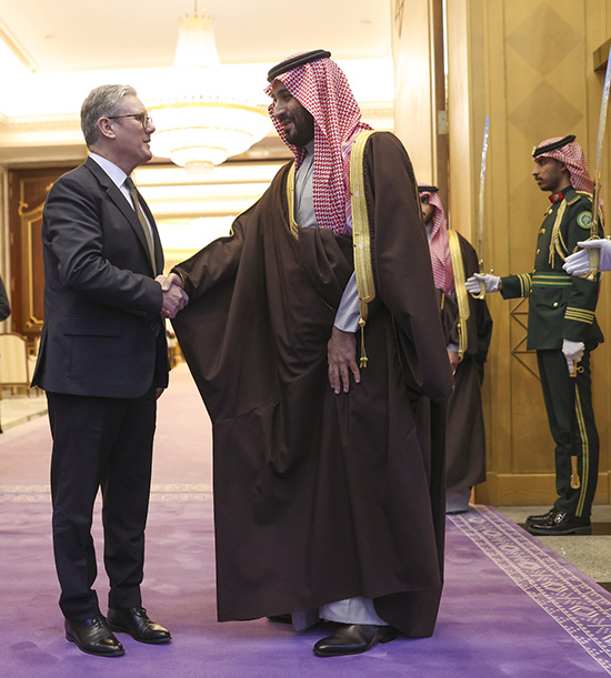 Mohamed ben Salmane et le premier ministre anglais Keir Starmer se serrent la main dans le couloir entourés de gardes saoudiennes