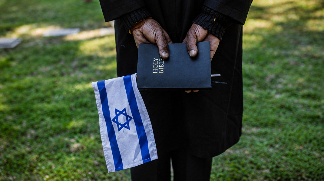 Un homme de dos tient une bible dans ses mains et un drapeau israélien