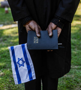 Un homme de dos tient une bible dans ses mains et un drapeau israélien