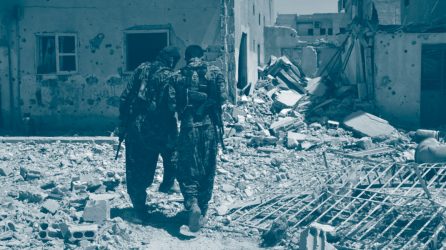 Deux combattants, membres des Forces démocratiques syriennes entre les décombres à Raqqa, parlent entre eux en tournant le dos au photographe
