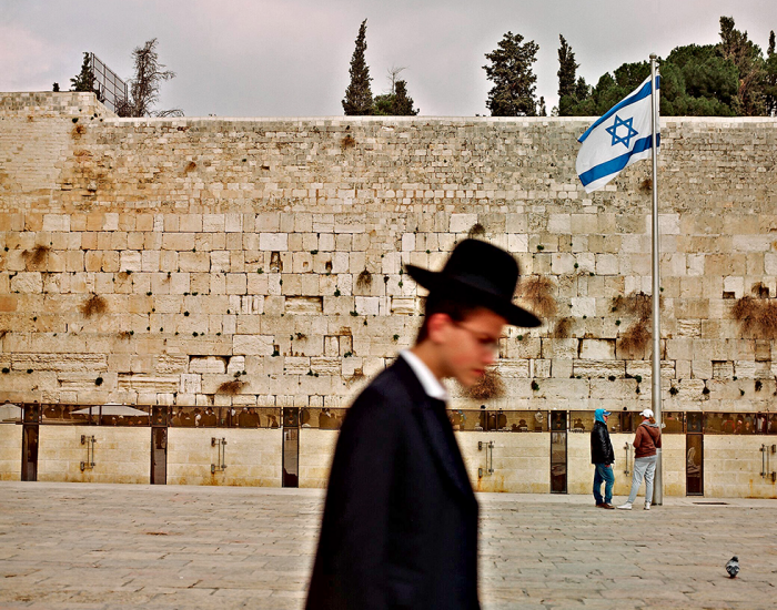orthodoxe israélien passe devant le mur des lamentations avec un drapeau israélien sur le fond