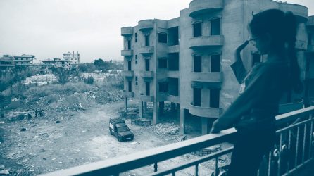 une jeune fille sur un balcon à Beyrouth salue une personne en bas de son immeuble entouré de ruines