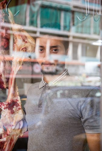 Un jeune boucher libanais derrrière les reflêts d'une vitrine
