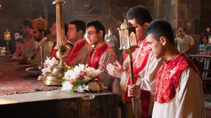Quatre prêtres en toges rouges se tiennent devant l'autel dans une église