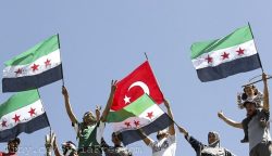 Syrian refugees wave Turkish and Syrian Independence flags during a protest against Assad at Yayladagi refugee camp in Hatay province on the Turkish-Syrian border April 10, 2012.